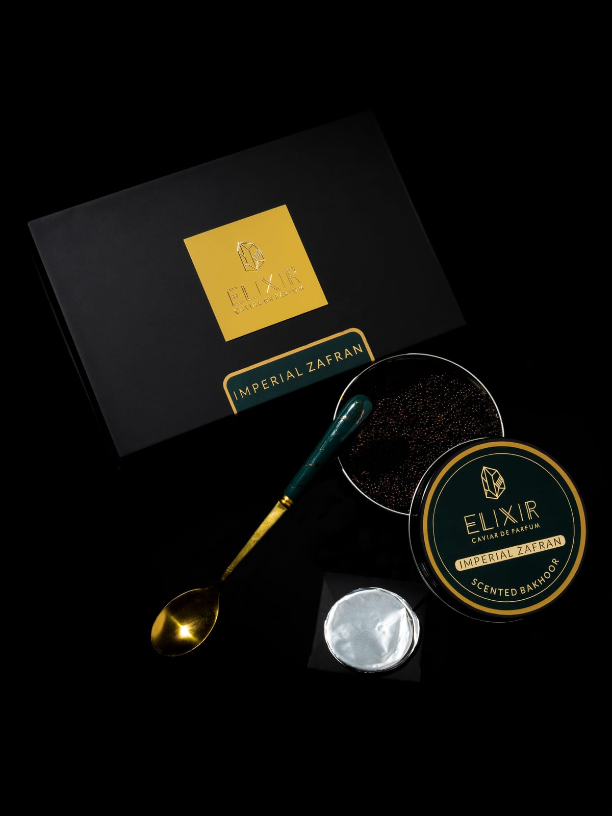 The Imperial Zafran box open on black, its green-lidded tin and a spoon of pearls